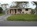 Front view of a ranch house with a carport and a well-maintained lawn at 11798 104Th St, Largo, FL 33773