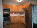 L-shaped kitchen with wood cabinets, stainless steel appliances, and tile backsplash at 11798 104Th St, Largo, FL 33773