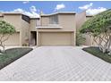 Townhouse exterior featuring a garage, landscaping and a brick driveway at 13804 Mill Cove Cir, Tampa, FL 33618