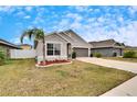 One-story house with gray exterior, two-car garage, and palm tree at 14525 Scottburgh Glen Dr, Wimauma, FL 33598