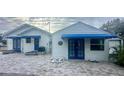 White house with blue awnings and brick paver patio. Two building structures at 410 W Lemon St, Tarpon Springs, FL 34689