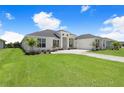 A view of the home's front exterior featuring manicured lawns and a driveway to the four-car garage at 5112 Lake Toscana Dr, Wimauma, FL 33598