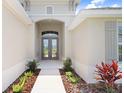 Close-up of a home's entrance with double doors, complemented by landscaped foliage and stylish exterior finishes at 5214 Lake Venice Dr, Wimauma, FL 33598