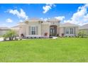 Inviting home exterior featuring a lush green lawn, well-placed shrubbery, and a neutral-toned facade at 5214 Lake Venice Dr, Wimauma, FL 33598