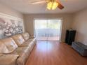 Living room with sliding glass doors to balcony, leather couch, and hardwood floors at 100 Waverly Way # 201, Clearwater, FL 33756
