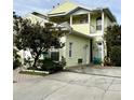 Two-story yellow house with a balcony and a tree in the front at 458 Grant St, Dunedin, FL 34698