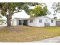 White single story home with a screened porch and mature landscaping at 9825 Lakeside Ln, Port Richey, FL 34668