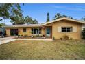 Tan single-story house with teal front door and landscaping at 1034 Sunnydale Dr, Clearwater, FL 33755