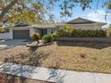 Front yard view of a house with a gray garage door and landscaping at 1695 Honeybear Ln, Dunedin, FL 34698