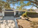 House exterior with gray garage door and mature trees in the front yard at 1695 Honeybear Ln, Dunedin, FL 34698