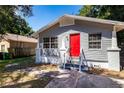 Gray house with red door, front yard, and concrete driveway at 2002 E Ellicott St, Tampa, FL 33610