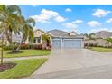 Two-story house with blue siding, three-car garage, and palm trees at 6645 Current Dr, Apollo Beach, FL 33572