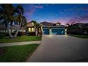 Beautiful twilight shot of a single-Gathering home with vibrant landscaping, a well-manicured lawn and a wide driveway at 6645 Current Dr, Apollo Beach, FL 33572