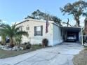 Front view of a mobile home with carport, American flag, and landscaped yard at 10538 Bay Hills Cir, Thonotosassa, FL 33592