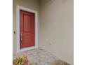 Red front door entry with a tiled stoop and small potted plant at 1575 N River Cir, Tarpon Springs, FL 34689