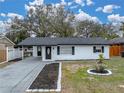 White brick ranch home with gray roof and well-maintained landscaping at 2104 W Okaloosa Ave, Tampa, FL 33604