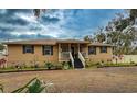 Tan house with dark shutters, front porch, landscaping, and large trees at 5805 34Th S Ave, Tampa, FL 33619