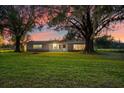 Charming single-story home with a well-manicured lawn and mature trees under a colorful evening sky at 10601 Paul S Buchman, Plant City, FL 33565