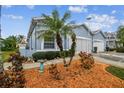 Side view of a light blue house with a two-car garage and landscaping at 11447 Golf Round Dr, New Port Richey, FL 34654