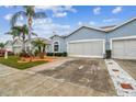 Side view of a light blue house with a two-car garage and landscaping at 11447 Golf Round Dr, New Port Richey, FL 34654