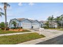 Street view of a light blue house with a two-car garage and landscaping at 11447 Golf Round Dr, New Port Richey, FL 34654