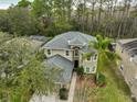 Two-story house, grey roof, surrounded by lush green trees at 12127 Luftburrow Ln, Hudson, FL 34669