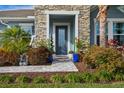 Inviting front entry with stone pillars, landscaping, and a gray door at 4449 Tour Trce, Land O Lakes, FL 34638