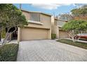 Front view of tan townhome with double garage and landscaping at 13810 Mill Cove Cir, Tampa, FL 33618