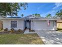 Gray house with American flag, two-car garage, and landscaped lawn at 19304 Garden Quilt Cir, Lutz, FL 33558