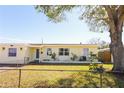 House exterior showcasing a light yellow painted home with a large tree in the front yard at 6554 34Th N Ave, St Petersburg, FL 33710
