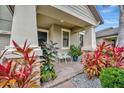 Covered front porch with seating area and tropical landscaping at 13355 Orca Sound Dr, Riverview, FL 33579