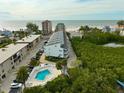 Aerial view showing condo complex with pool, ocean, and tropical foliage at 19727 Gulf Blvd # 103, Indian Shores, FL 33785