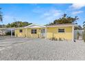 Charming yellow home featuring a well-maintained front yard with decorative rock and fresh landscaping at 3235 Merita Dr, Holiday, FL 34691