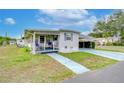 Side view of a white mobile home with a covered porch and landscaping at 37350 Tropical Dr, Zephyrhills, FL 33541