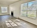 Bright living room with gray wood-look flooring, a fireplace, and two windows with natural light at 4208 Winding Moss Trl # 102, Tampa, FL 33613