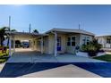 Tan single-story home with carport, blue door, and landscaping at 544 Skipper Dr # 544, Seminole, FL 33772