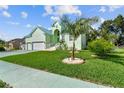 Attractive light green house with a three-car garage, palm tree, and manicured lawn at 711 Eagle Ln, Apollo Beach, FL 33572