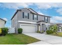 Two-story house with gray siding, neutral garage door, and landscaped lawn at 13614 Wild Ginger St, Riverview, FL 33579