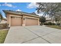 Tan two-car garage with attached house and large driveway at 4381 Caliquen Dr, Brooksville, FL 34604