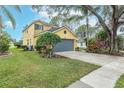 Two-story yellow house with gray garage door and well manicured lawn at 5608 Rockfield Loop, Valrico, FL 33596