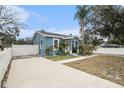 The home's exterior boasts a light blue paint job, concrete driveway, and a white fence at 8907 N Boulevard, Tampa, FL 33604