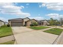 Houses with gray garage doors and green lawns at 13230 Wildflower Meadow Dr, Riverview, FL 33579