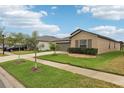 Tan house with gray garage door and landscaping at 13230 Wildflower Meadow Dr, Riverview, FL 33579