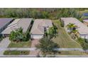 Aerial view showcasing a well-maintained home with manicured lawn, brick driveway, and beautiful tile roof at 16127 Cape Coral Dr, Wimauma, FL 33598