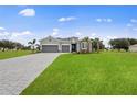 New home with gray siding, three car garage, and paver driveway at 15143 Sea Salt Way, Bradenton, FL 34211