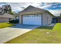 Side view of a house showcasing a white garage door and green lawn at 6932 Oakcrest Way, Zephyrhills, FL 33542