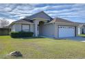 Front view of a single story house with a white garage door at 6932 Oakcrest Way, Zephyrhills, FL 33542