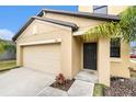 Tan house exterior featuring a dark brown door and garage at 7610 Blue Iris Ln, Tampa, FL 33619