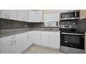 Modern kitchen featuring stainless steel appliances, granite counters, and white cabinets at 925 67Th S St, St Petersburg, FL 33707