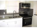 Modern kitchen boasting stainless steel appliances and dark gray backsplash at 925 67Th S St, St Petersburg, FL 33707